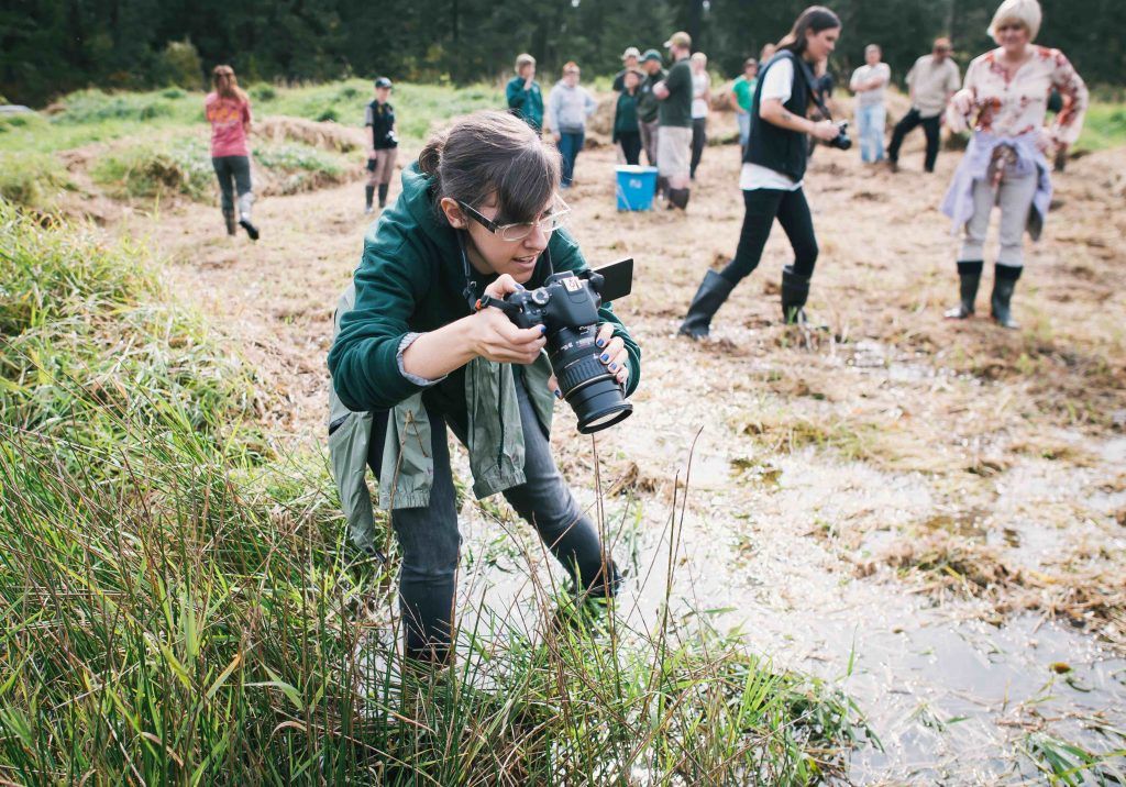 Woman in field with camera doing citizen science