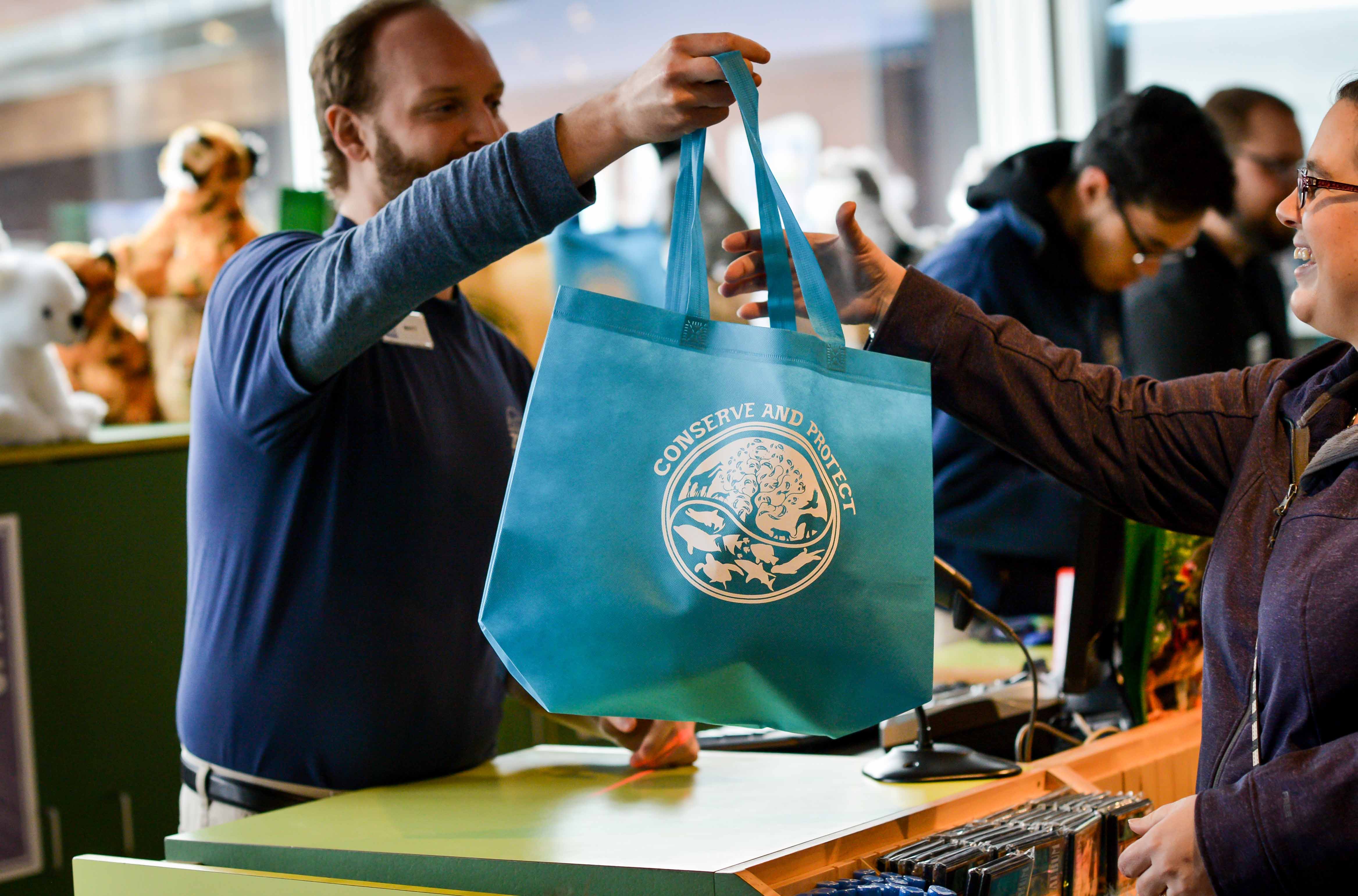 Staff holding reusable bag in gift shop.